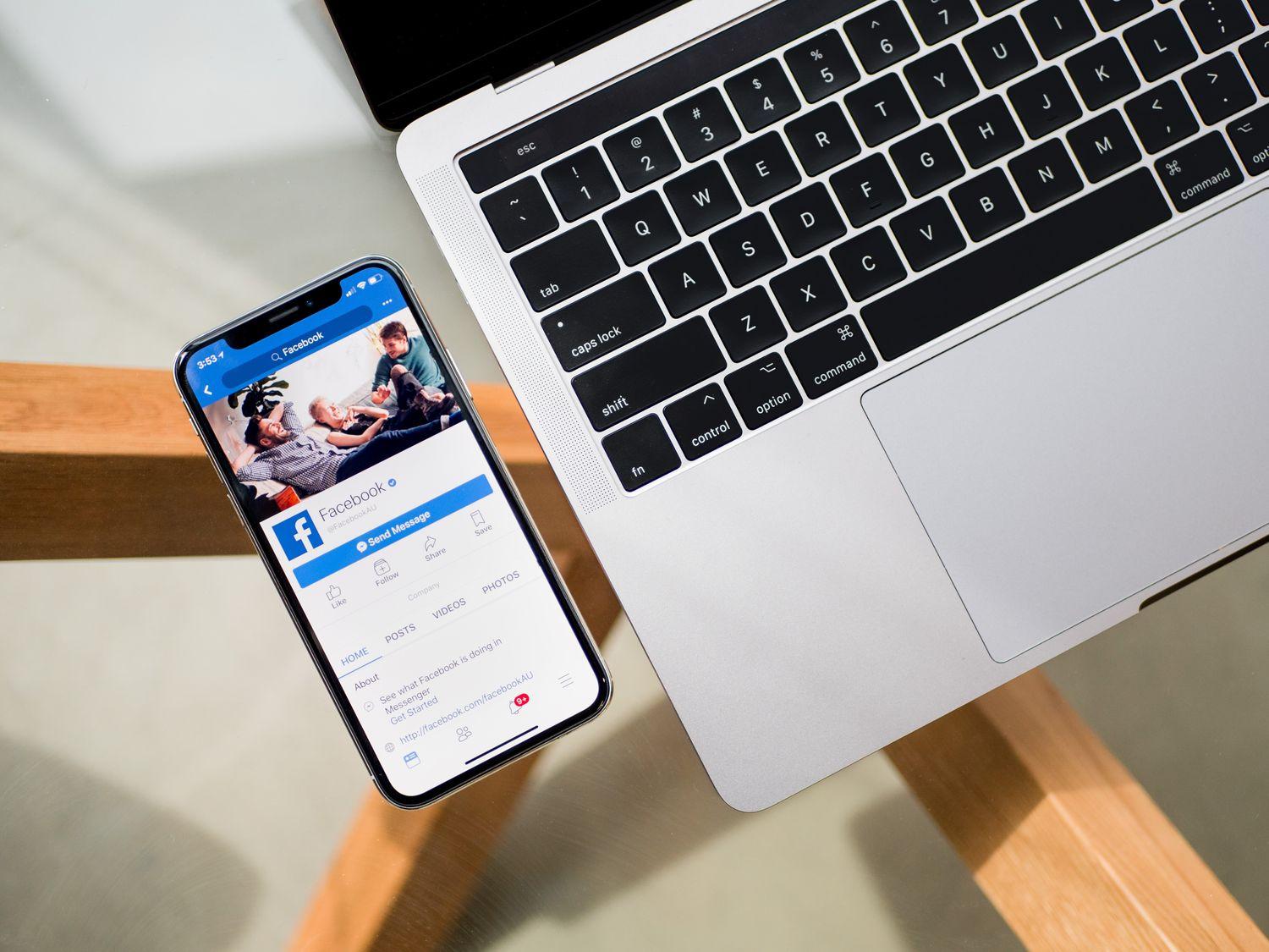 Facebook page on mobile next to macbook