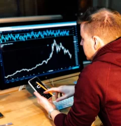 keyword rankings - red haired guy with a mobile phone in front of a chart on a black monitor