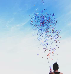nyx marcom awards - confetti thrown into the air by a girl against a blue sky