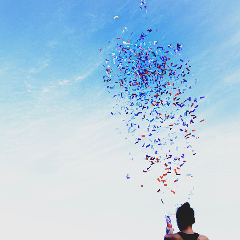 nyx marcom awards - confetti thrown into the air by a girl against a blue sky