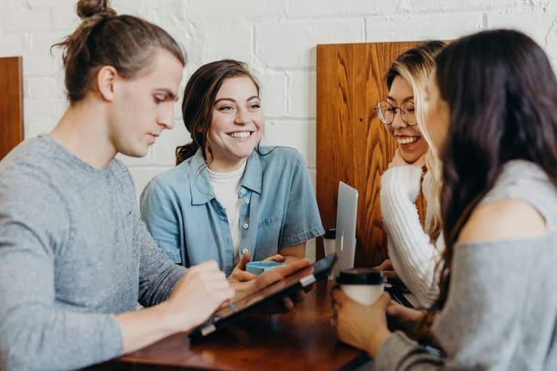 market research - group of people three girls and a guy smiling at a table