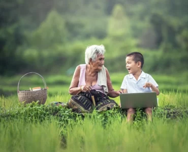 sustainable - old woman and child in a green field in Asia with a basket