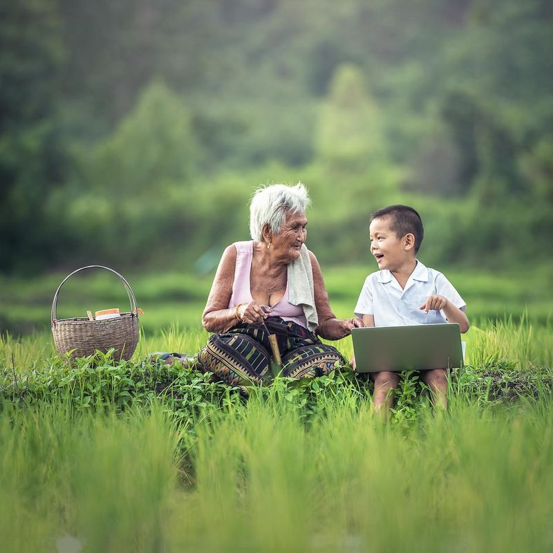 sustainable - old woman and child in a green field in Asia with a basket
